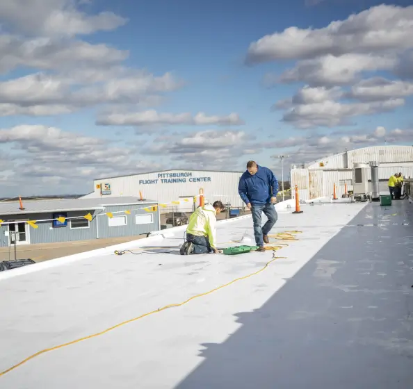 Commercial Roofing Contractor on roof at Pittsburgh Flight Training Center completing a commercial roof inspection